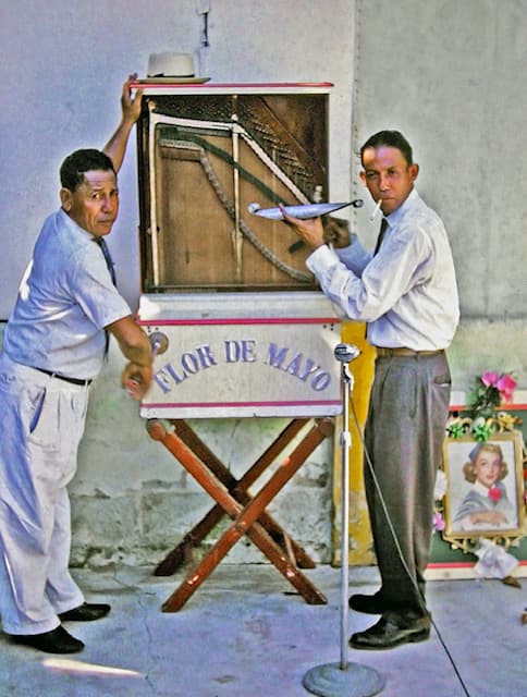 Two men with the Flor de Mayo Caha di Orgel barrel organ - a treasured piece of Aruban musical heritage